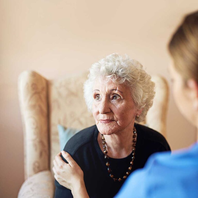 An older adult in a comfortable room using a tablet device with large, easy-to-read icons on the screen.